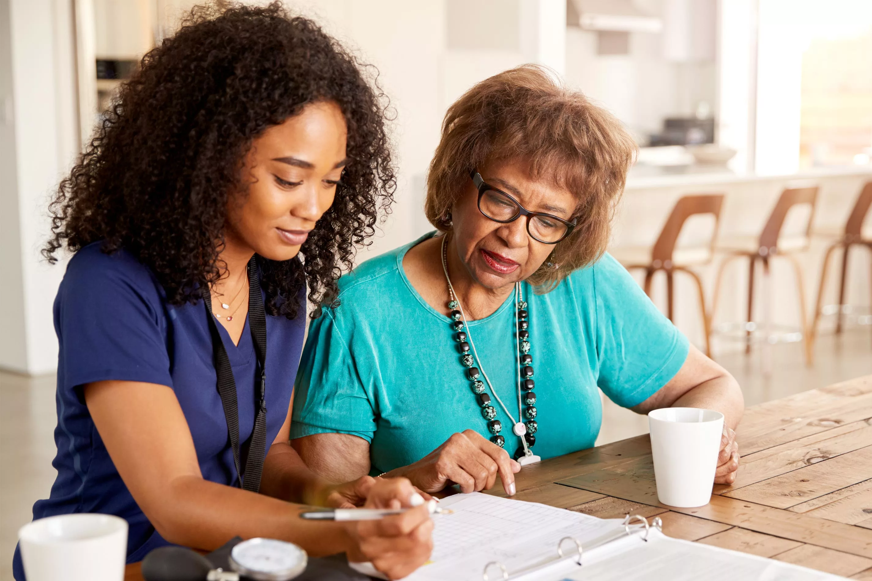 Employee in scrubs assisting patient with paperwork in a home